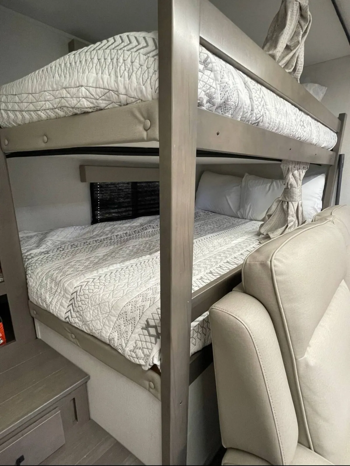 A warm, inviting view of a bunk bed area inside the RV, featuring textured bedding and comfortable seating. The layout emphasizes the cozy sleeping quarters designed for kids or guests, with elements that highlight family bonding and restful nights.