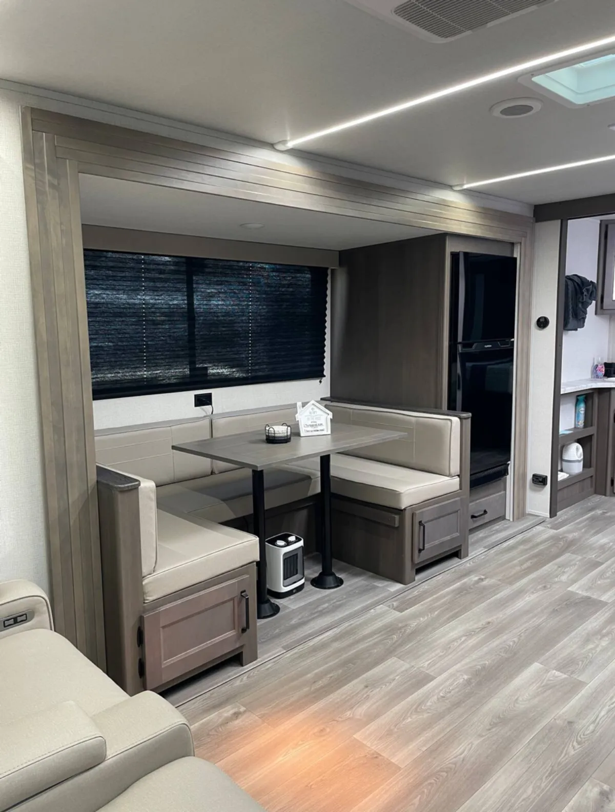 This image showcases the cozy RV interior with a clear view of the dining table, surrounding seating area, and essential kitchen appliances. The scene suggests a welcoming environment perfect for family meals, game nights, or casual gatherings, highlighting both the kitchen and dining area in a single shot.