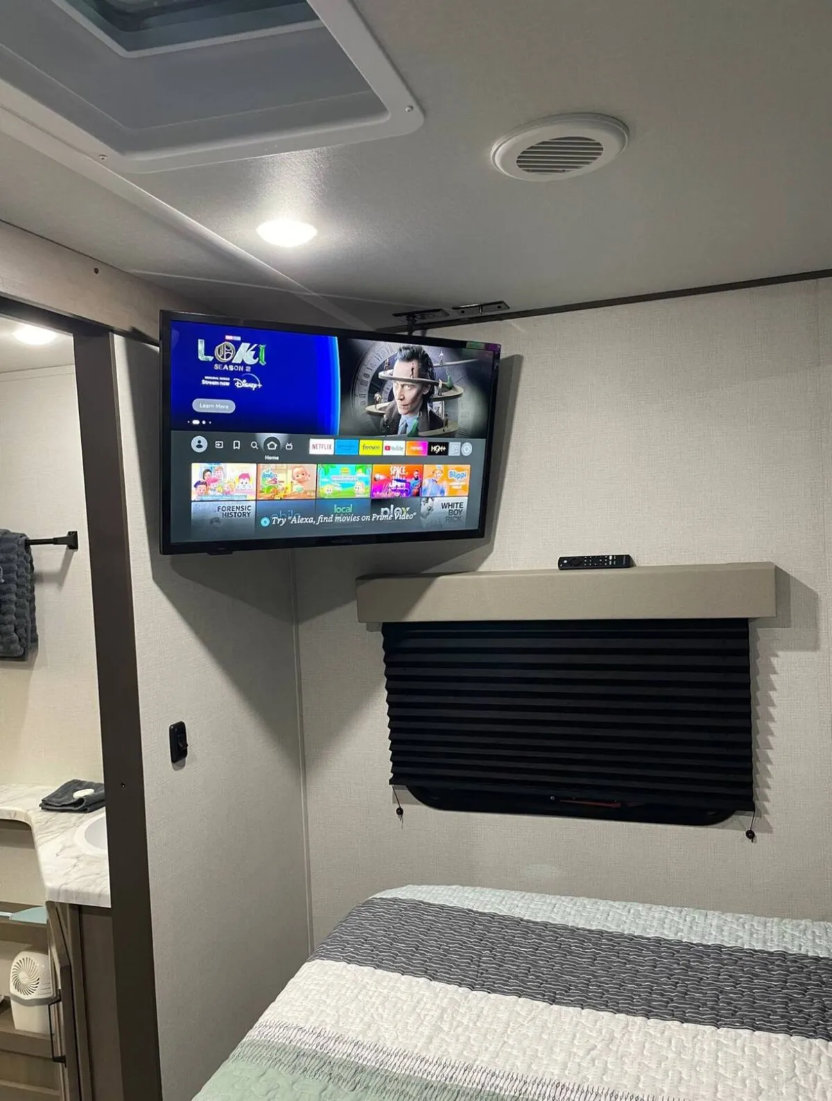 A comfortable sleeping area with a queen bed, complemented by window shades and a television nearby. The scene exudes relaxation, perfect for parents or couples seeking a bit of privacy and comfort after a long day.